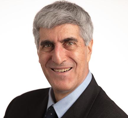 Head shot of gray haired smiling man in dark suit