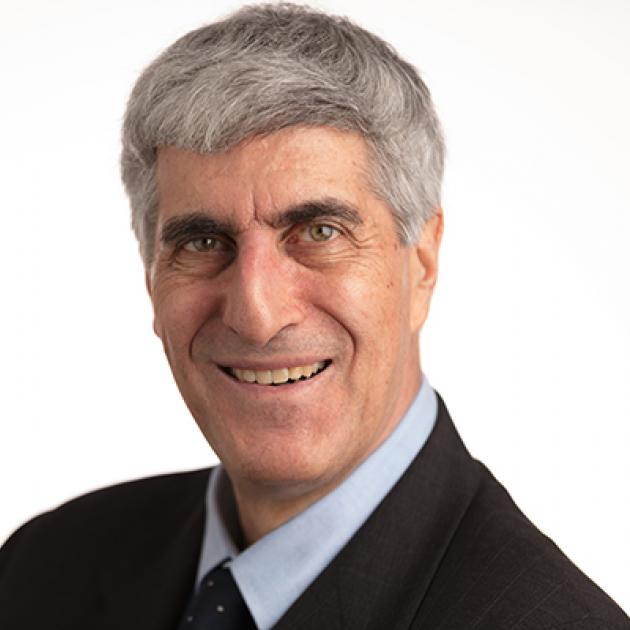 Head shot of gray haired smiling man in dark suit