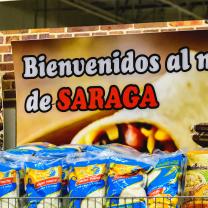 Sign in back of food at a grocery store saying Bienvenidos al de Saraga