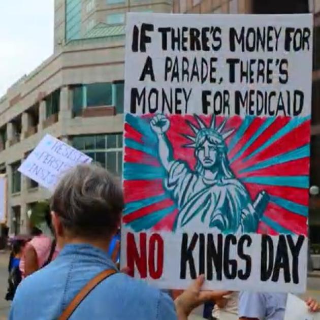 Protester holding sign saying If there's money for a parade there's money for Medicaid