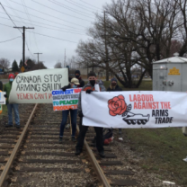 People holding signs on a railroad track